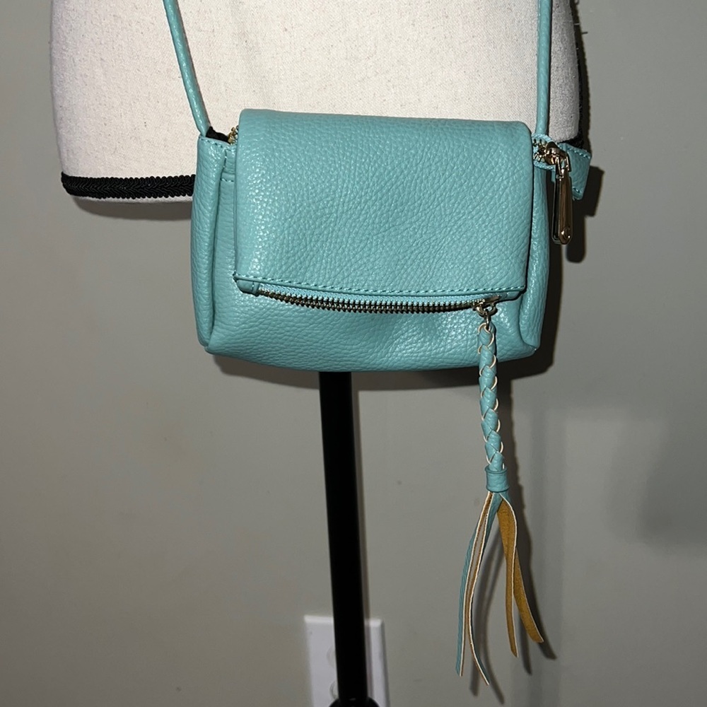 Small crossbody with tasseled zipper snaps close has inside pockets